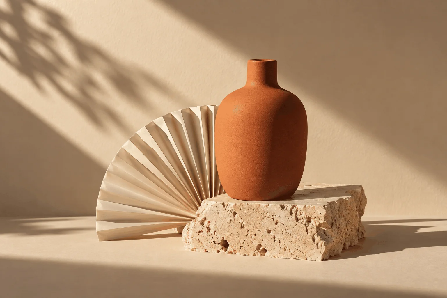 Conceptual still life of terracotta ceramics, folded paper and stone, lit from the side